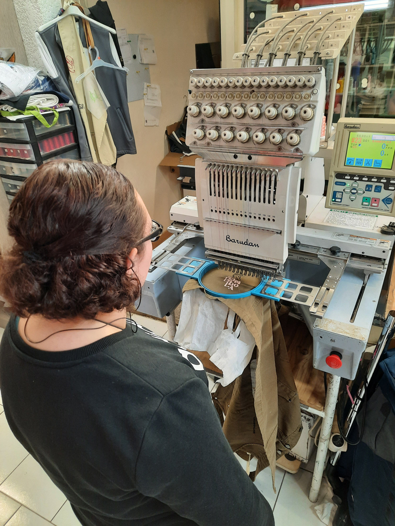 Jeune adulte en situation de handicap utilisant une machine de broderie dans le cadre du SESSAD Pro insertion professionnelle